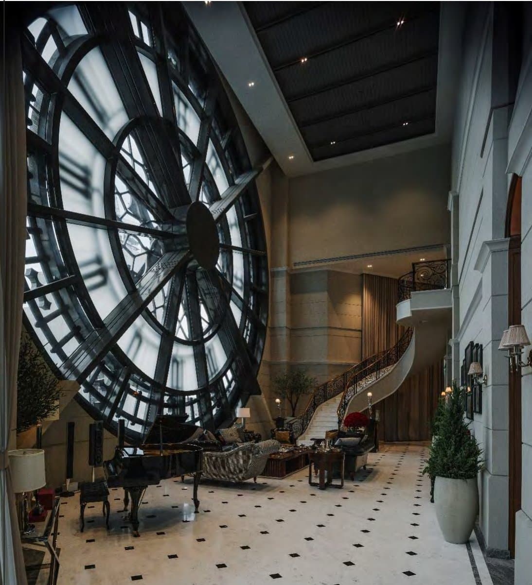 Double-height salon dominated by a storey-tall glazed clock face, curved wrought-iron staircase, black grand piano and checkerboard marble floor.