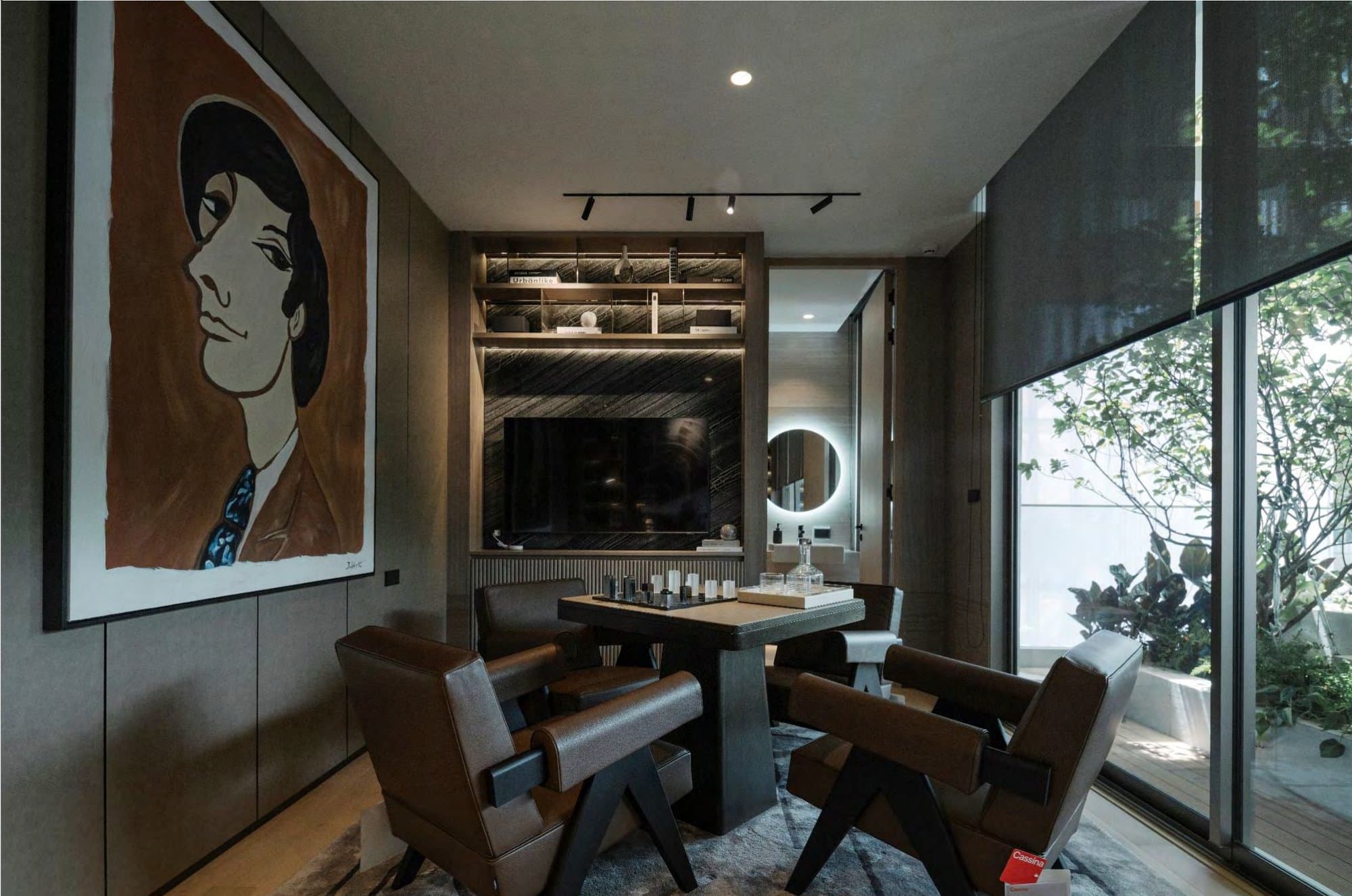 Media den with a striking portrait painting, dark stone TV niche, leather Chandigarh-style chairs, chess table and full-height garden window